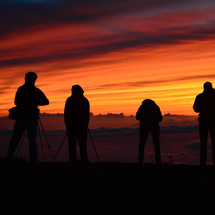otografen in Silhouette vor einem dramatischen Sonnenuntergang am Haleakalā National Park, Maui, Hawaii