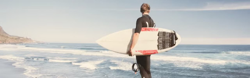 Activity Card A man with a wetsuit and surfboard by the sea