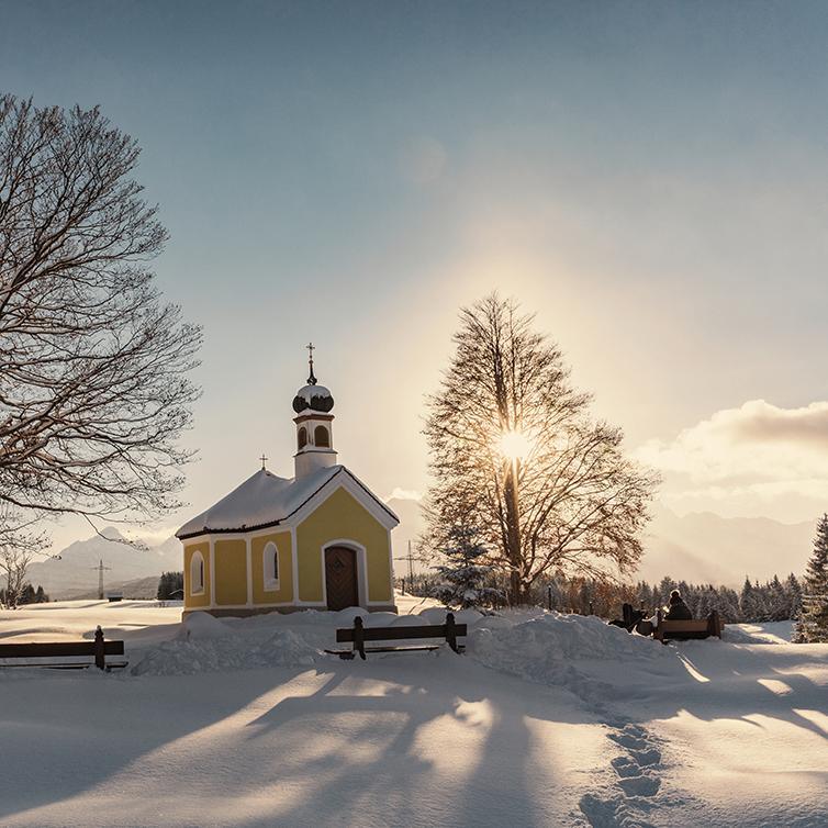View of a small chapel in Bavaria in a field of snow on a sunny day