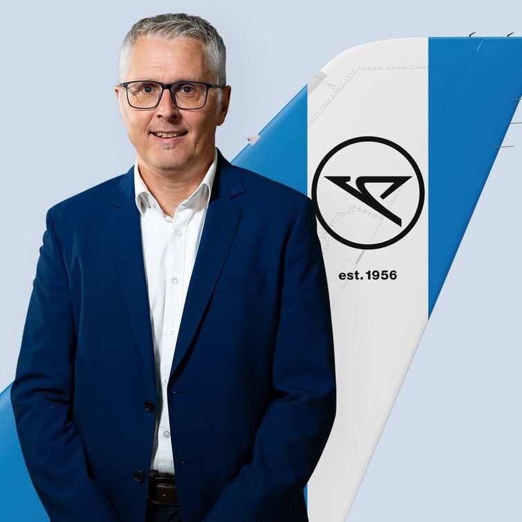 Heiko Holm CTO von Condor steht vor einem blau-weiß gestreiften Winglet von Condor