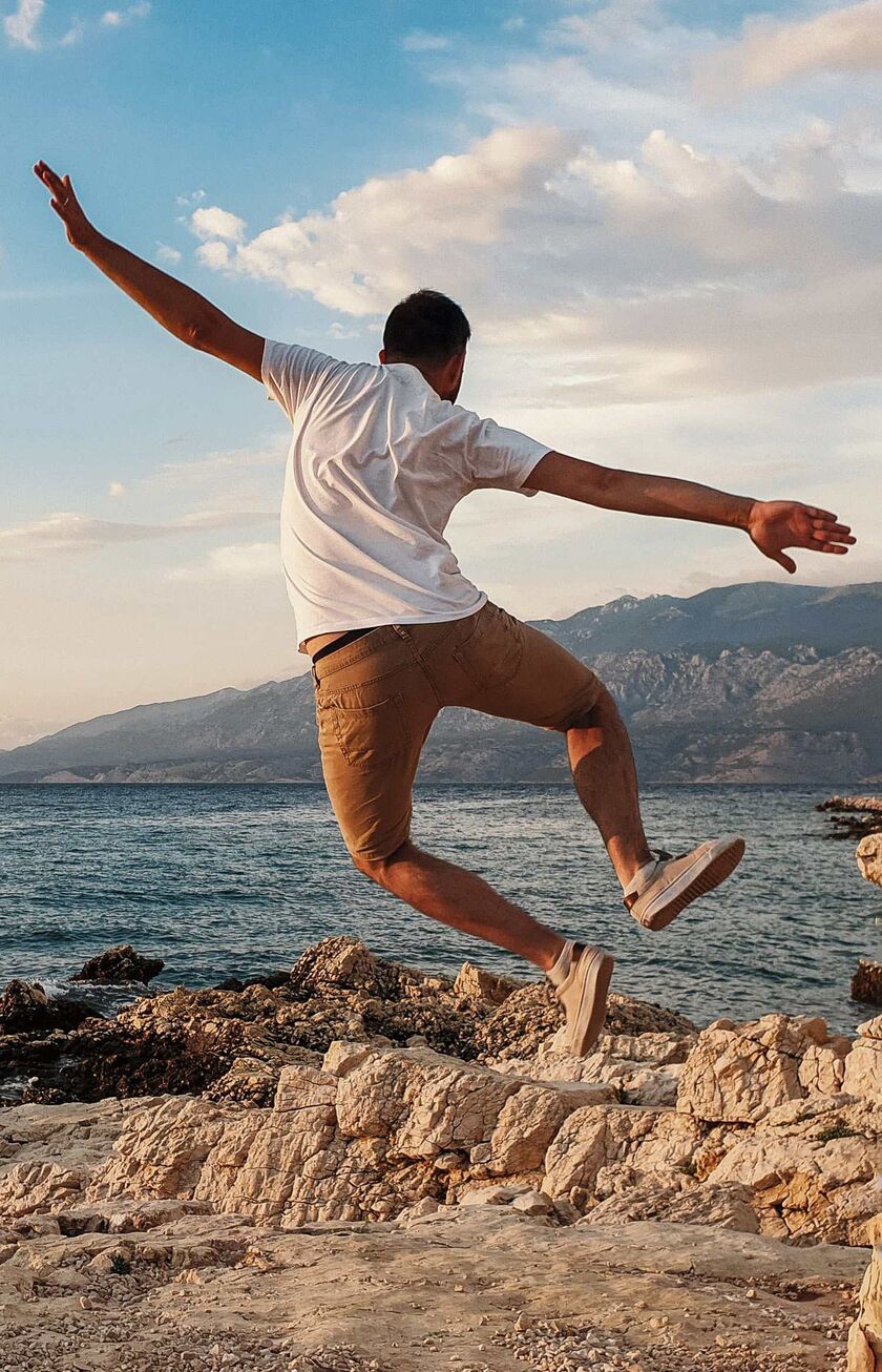 Mann auf dem Rücken springt vor Freude an der kroatischen Küste