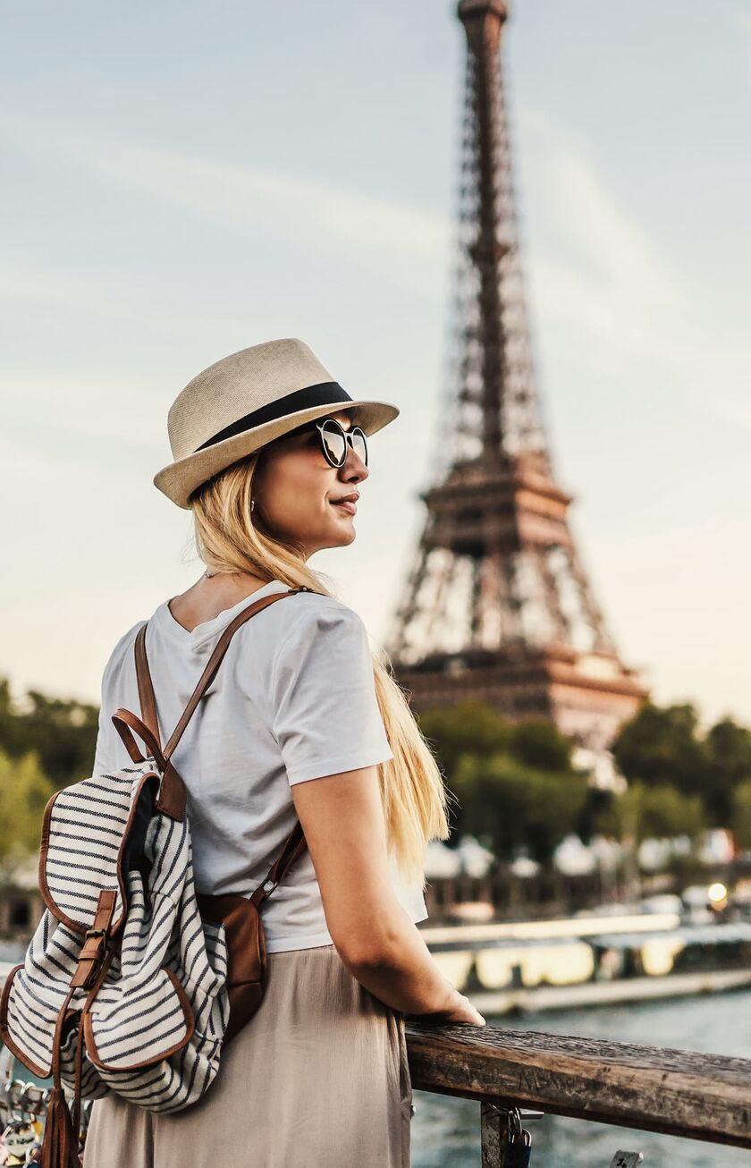 Frau mit Hut schaut auf den Pariser Eifelturm Frau mit Hut schaut auf den Pariser Eifelturm