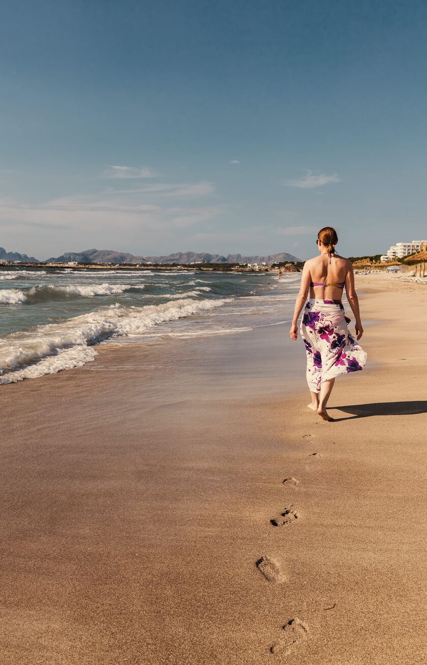 Frau spaziert allein an einem Strand an der spanischen Küste Frau spaziert allein an einem Strand an der spanischen Küste