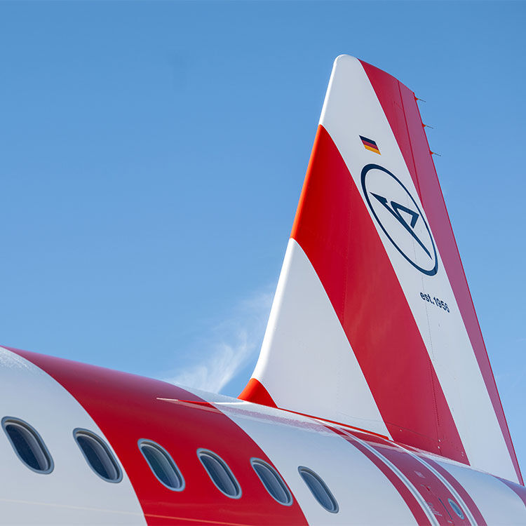 Das Heck eines rot-weiß gestreiften Flugzeugs mit dem Condor Logo