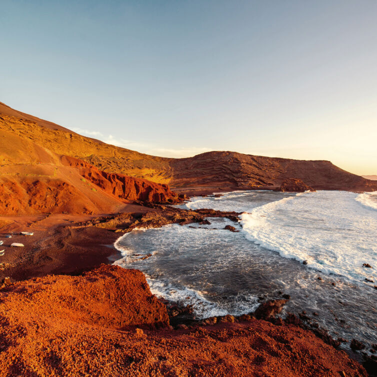 Rote Felsküste von Lanzarote, Bucht mit Wellen bei Sonnenuntergang