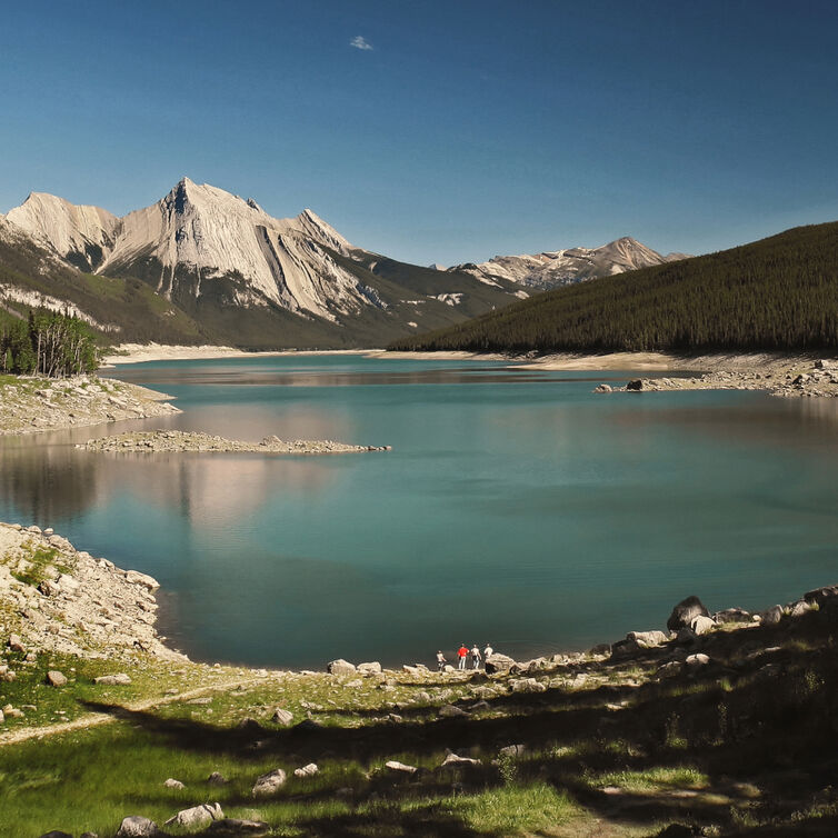 Medicine Lake in Jasper Nationalpark, umgeben von Bergen, klarem türkisfarbenen Wasser und grüner Landschaft