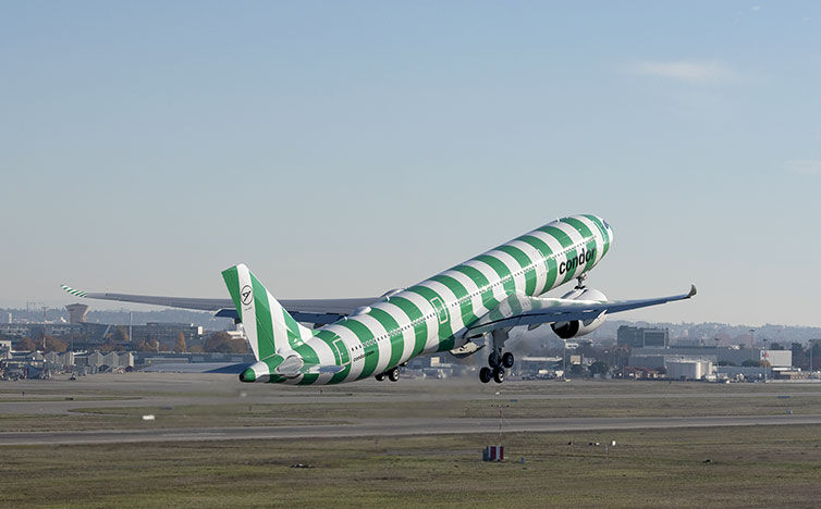 En grøn og hvid Airbus A330neo letter på asfalten.