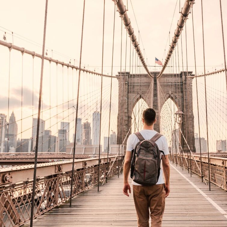 Hombre de espaldas cruzando a pie el Puente de Brooklyn, en Nueva York