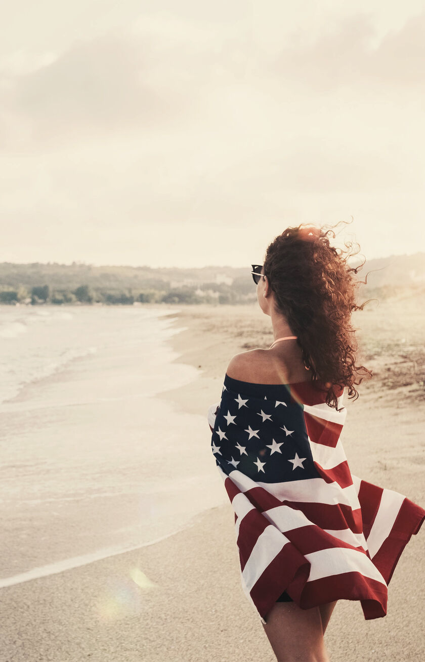 Mujer en la playa en Los Angeles (LAX) con bandera de los EE.UU.