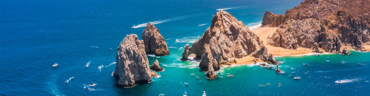 View of the famous rock formations at Los Cabos, Mexico, surrounded by turquoise waters and boats