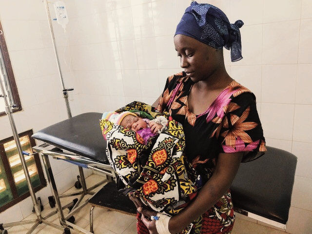 Mother with baby in her arms in a hospital ward.