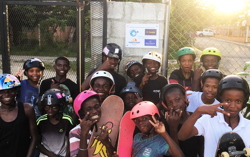 Children stand at the skate park with their skateboards in their hands. 