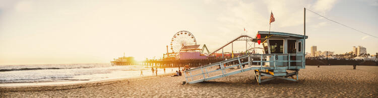 Spiaggia di Santa Monica con il famoso molo e ruota panoramica al tramonto.