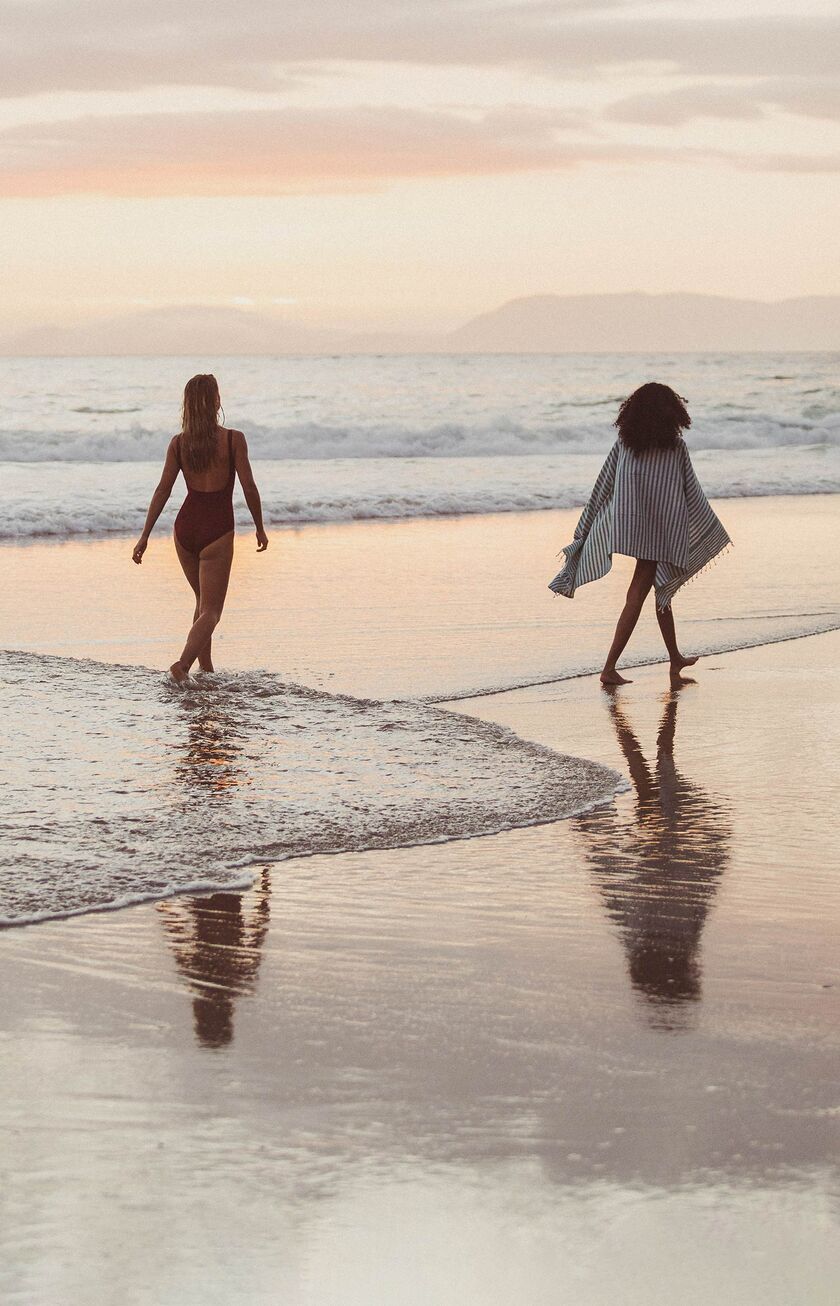 Donne che passeggiano sulla spiaggia al tramonto
