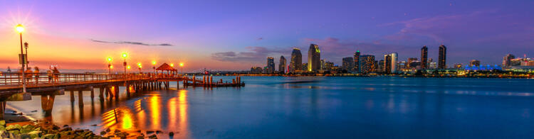 San Diego skyline bij nacht, gezien vanaf de baai met een verlichte pier op de voorgrond.