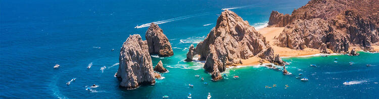 Een luchtfoto van de rotsformaties van Cabo San Lucas, omringd door blauwe zee en boten