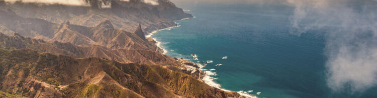 Kustlijn van Tenerife met bergen en de oceaan onder een bewolkte hemel.