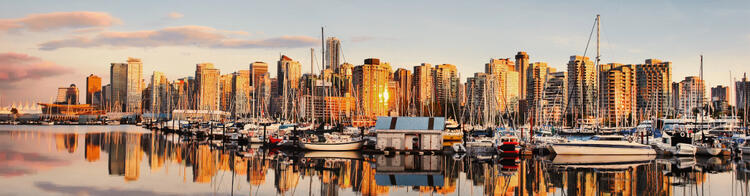 Skyline van Vancouver bij zonsondergang, met boten in de haven en de stad op de achtergrond.