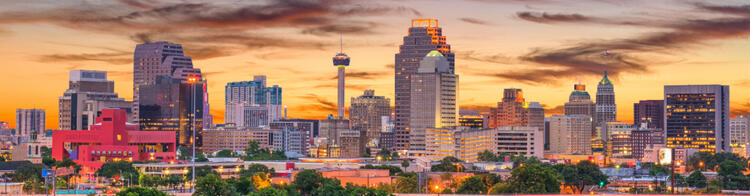 San Antonio skyline bij zonsondergang met kleurrijke wolken en stadslichten.