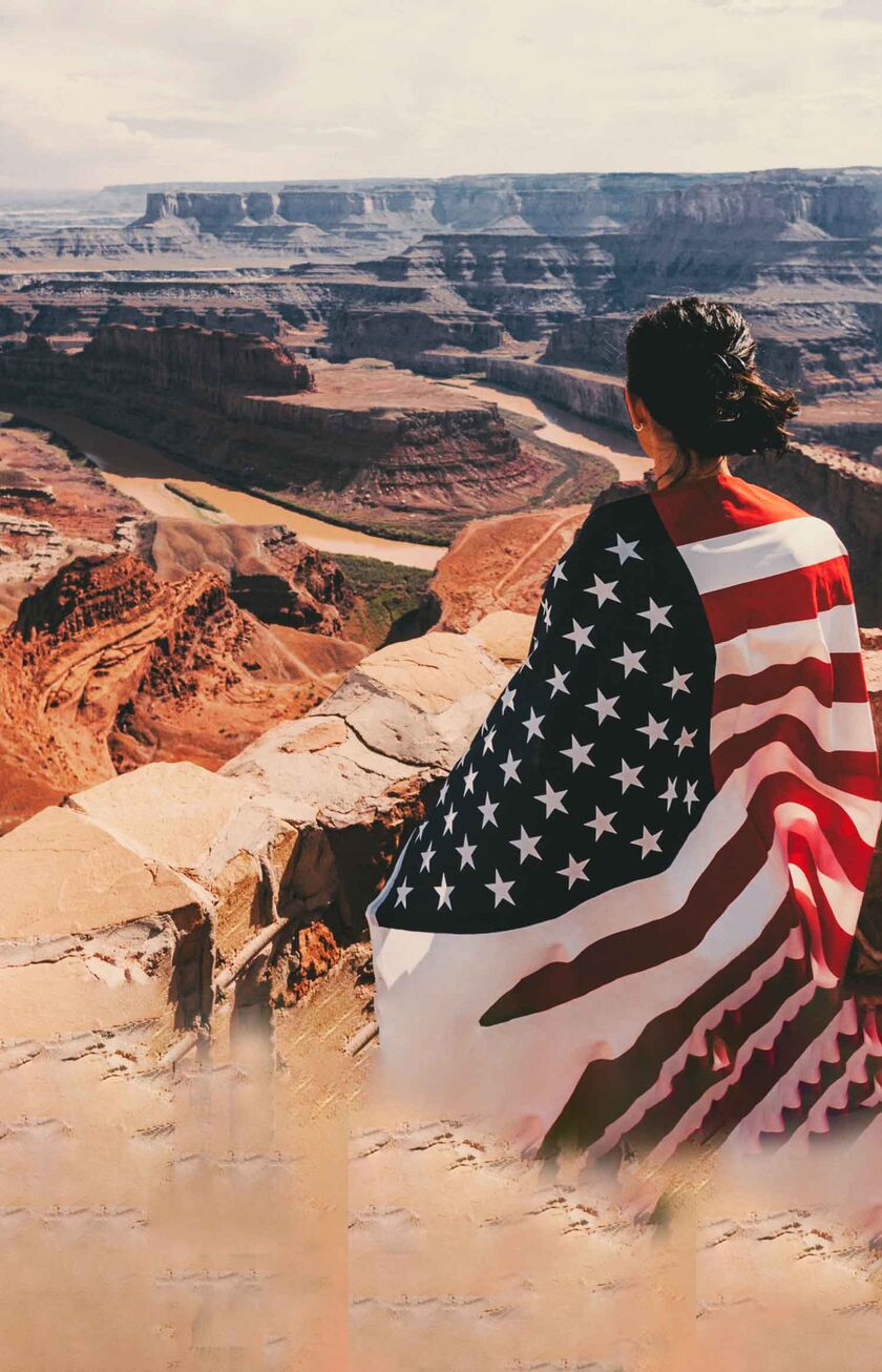 Uma mulher com a bandeira dos EUA olha para o Grand Canyon