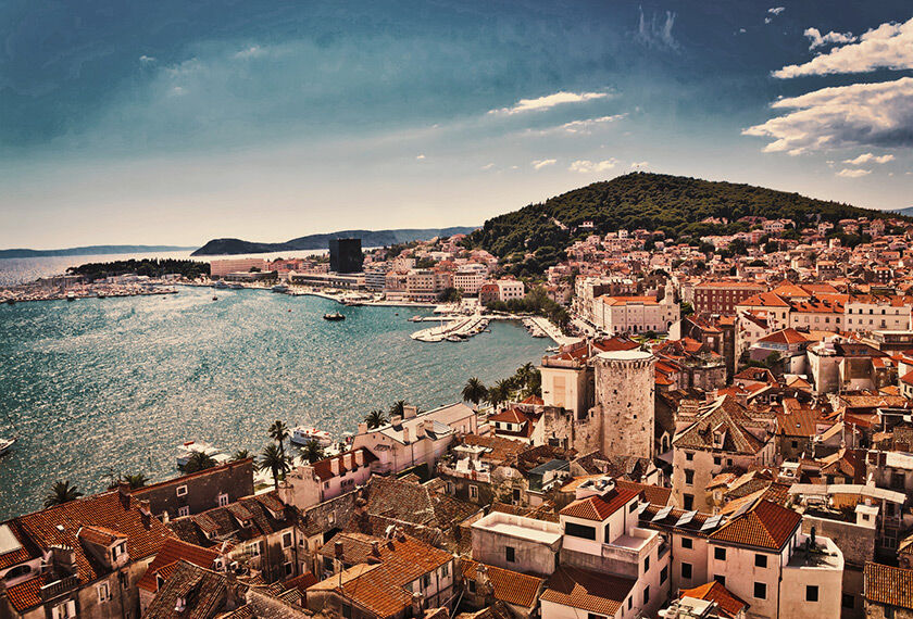 Panoramic view of a Split with terracotta roofs, overlooking a clear blue sea.